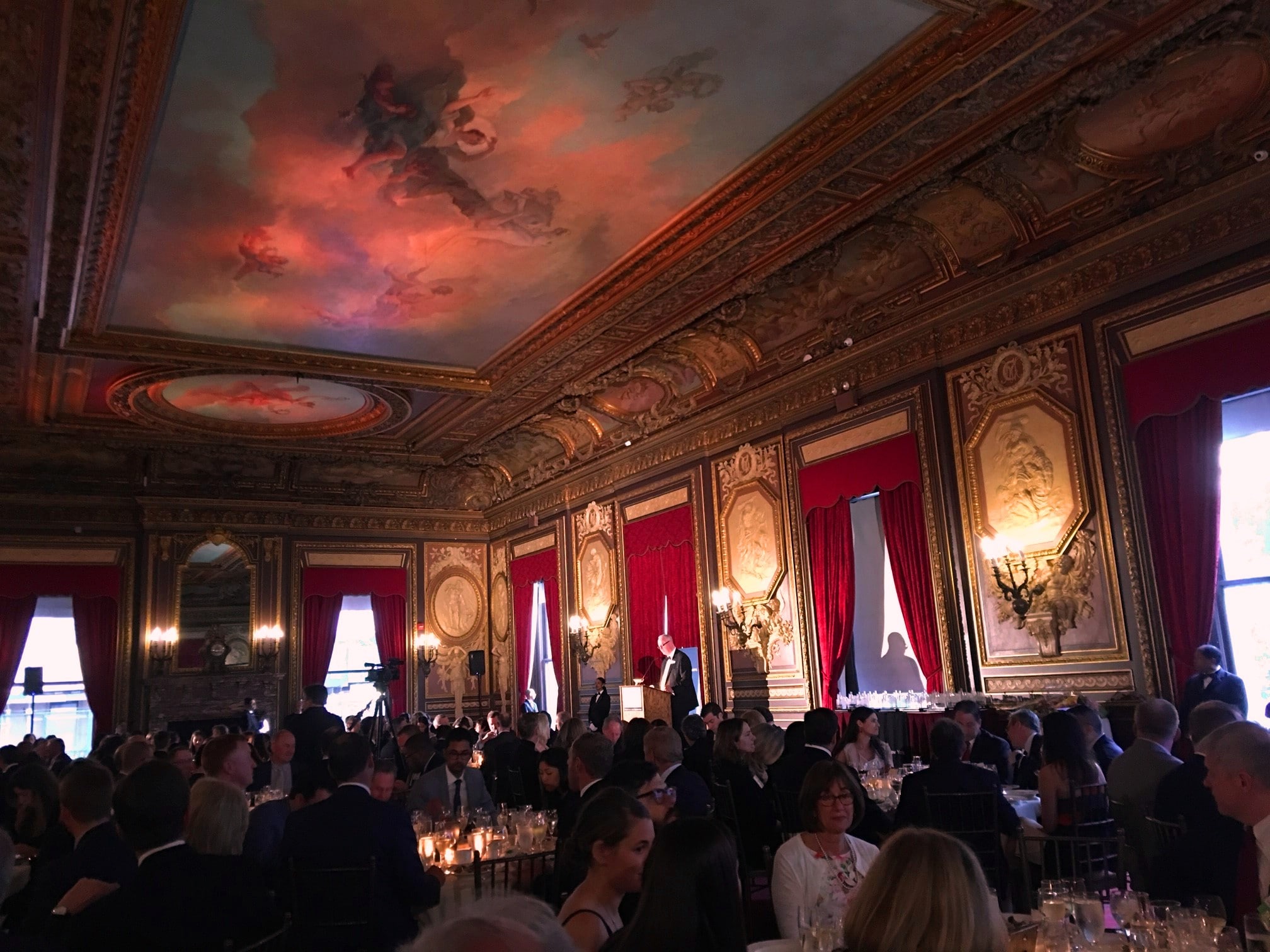 New York City Ballroom with painted ceiling and artwork on walls. People dining at tables.