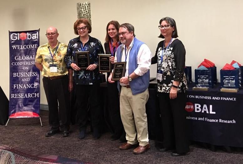 Two men and three women from Birchtree Global pose holding their awards