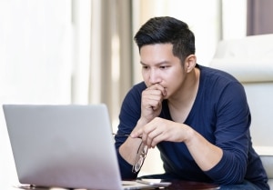 Young male watching webinar on laptop