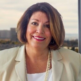 Daya Haines Haddock wearing business jacket white shirt and a pearl necklace around her neck