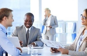 Two business man and one woman sit at table talking.